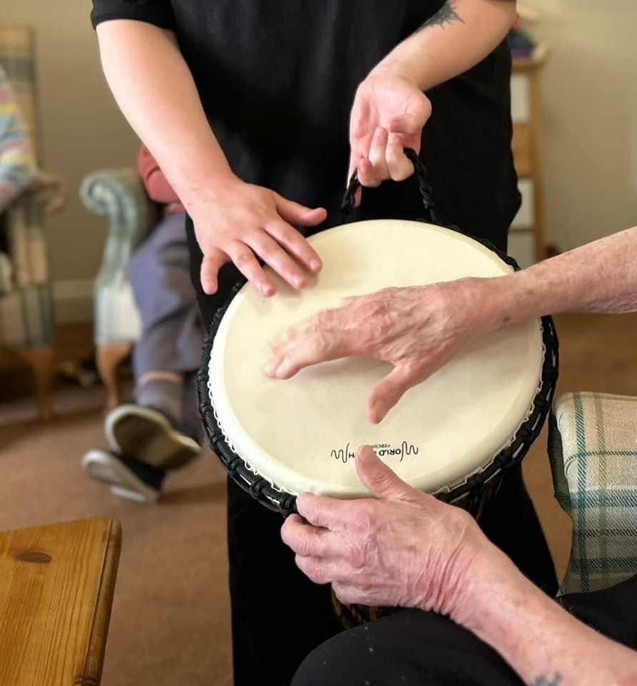 Hands playing a drum together during a music therapy session